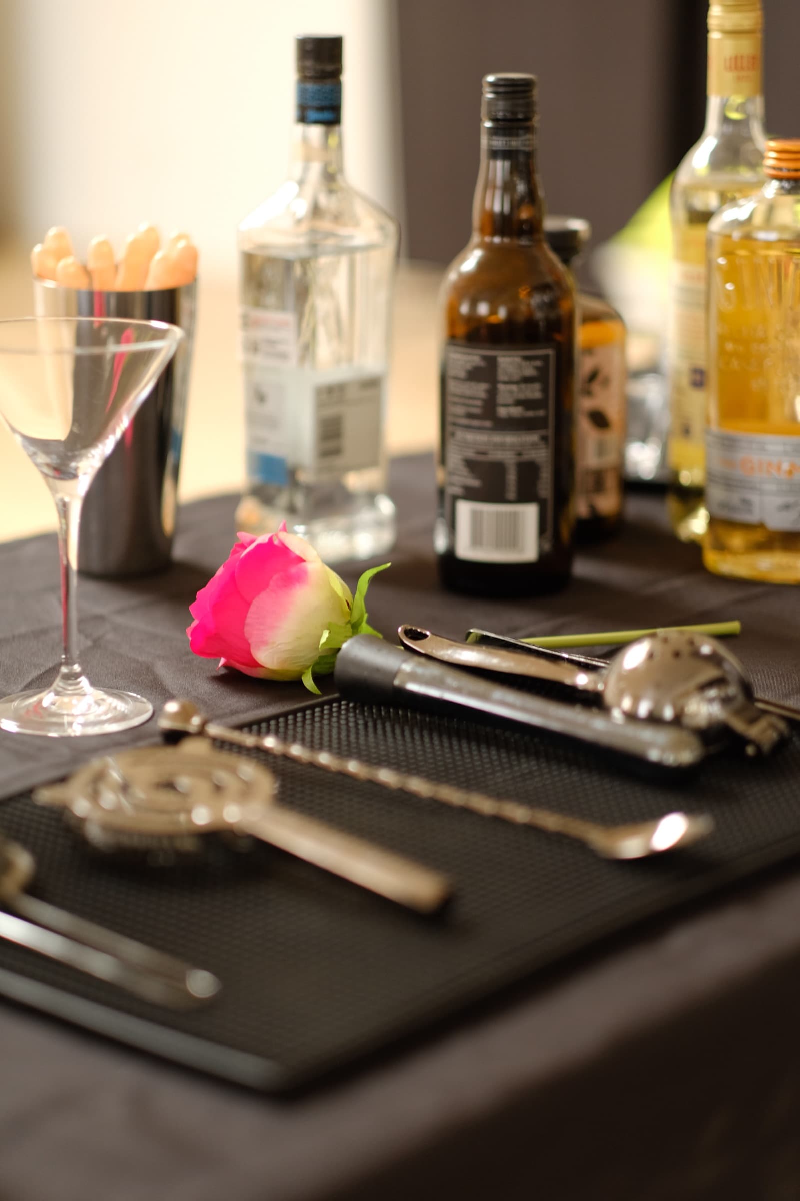 Cocktail tools, bottles and a rose set out for a hens party.